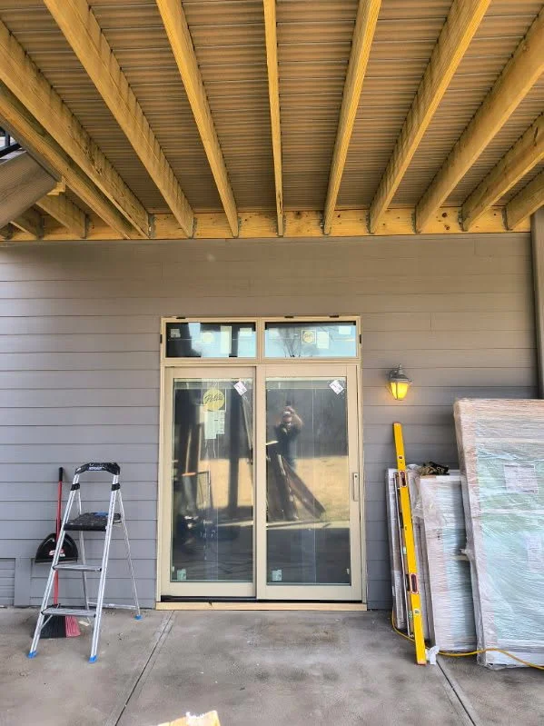 Entry door and sidelights being installed beneath a covered porch