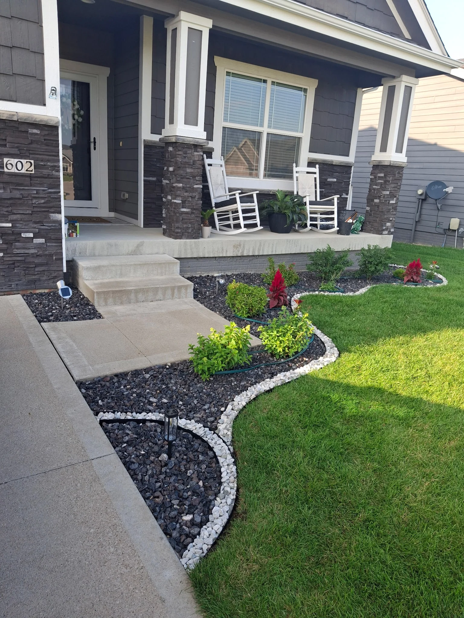 Finished front porch landscape beds with stone edging and plants
