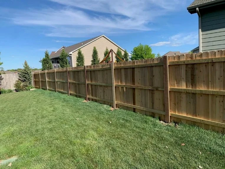 Finished wood privacy fence beside a green lawn